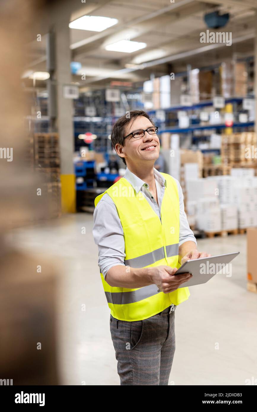 Sorridente lavoratore di magazzino con tablet PC che lavora in warehouse Foto Stock