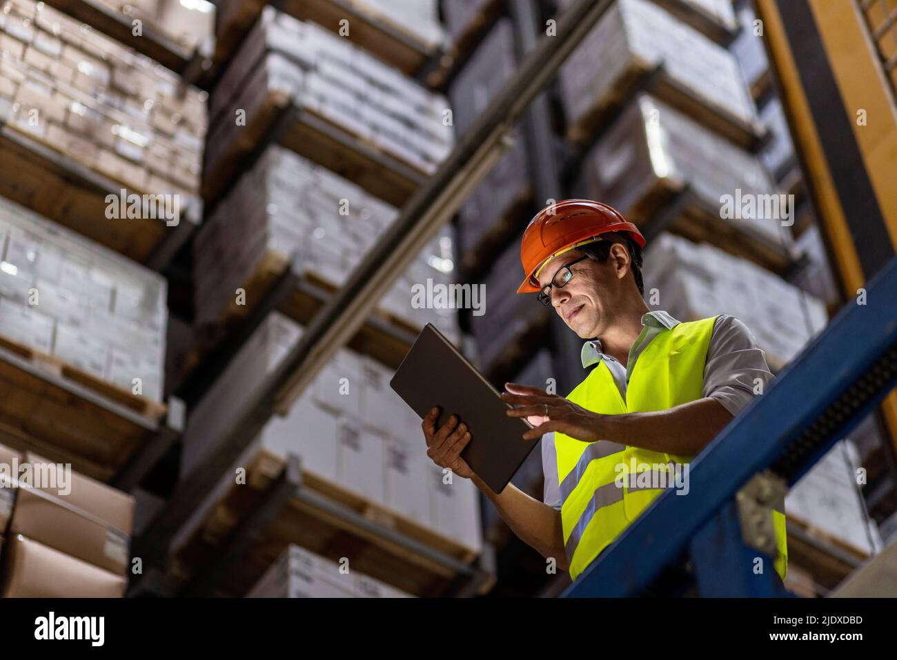 Operatore che indossa occhiali elenco di controllo sul tablet PC in magazzino Foto Stock