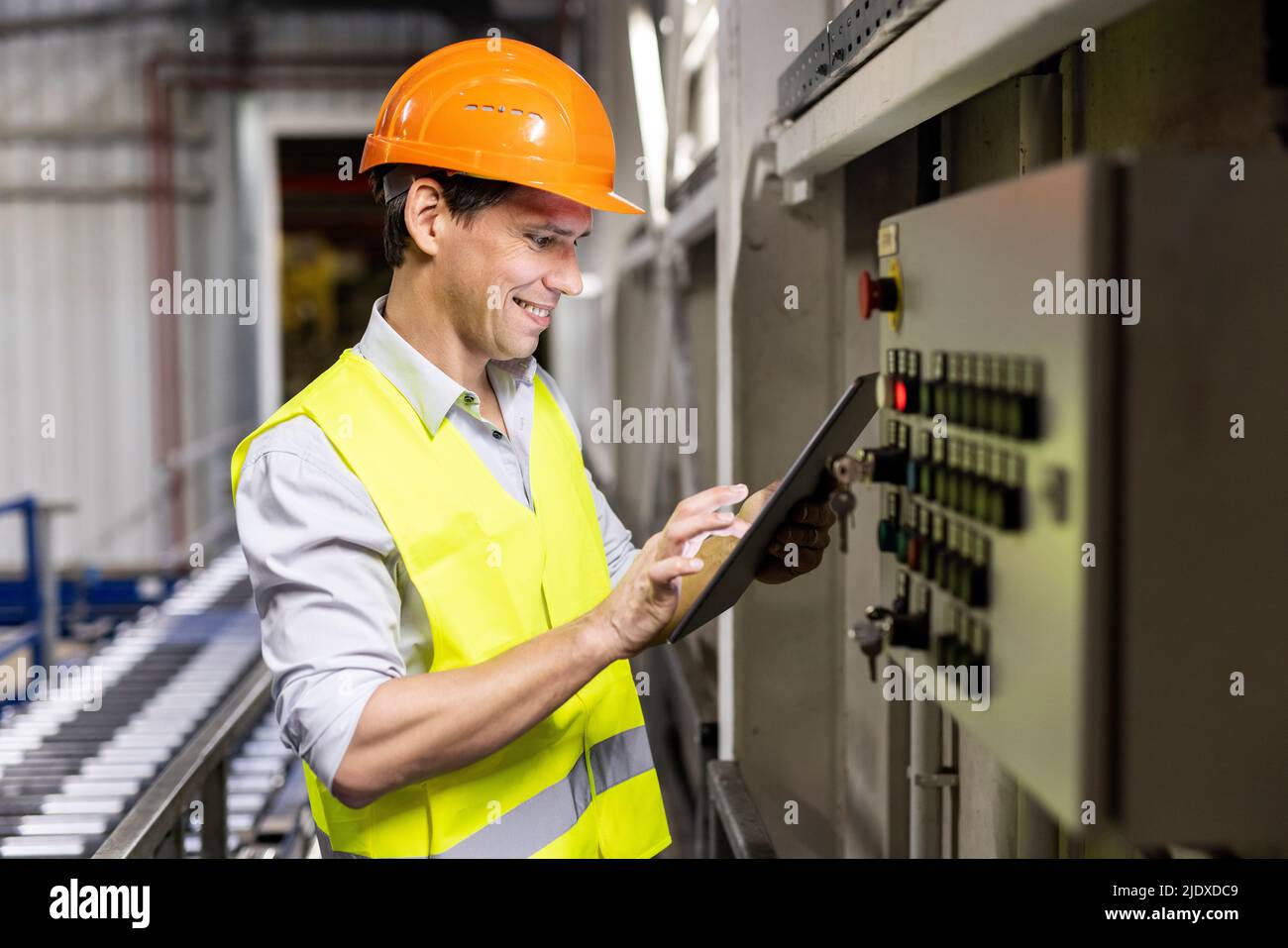 Sorridente lavoratore che utilizza un tablet PC dal pannello di controllo in warehouse Foto Stock