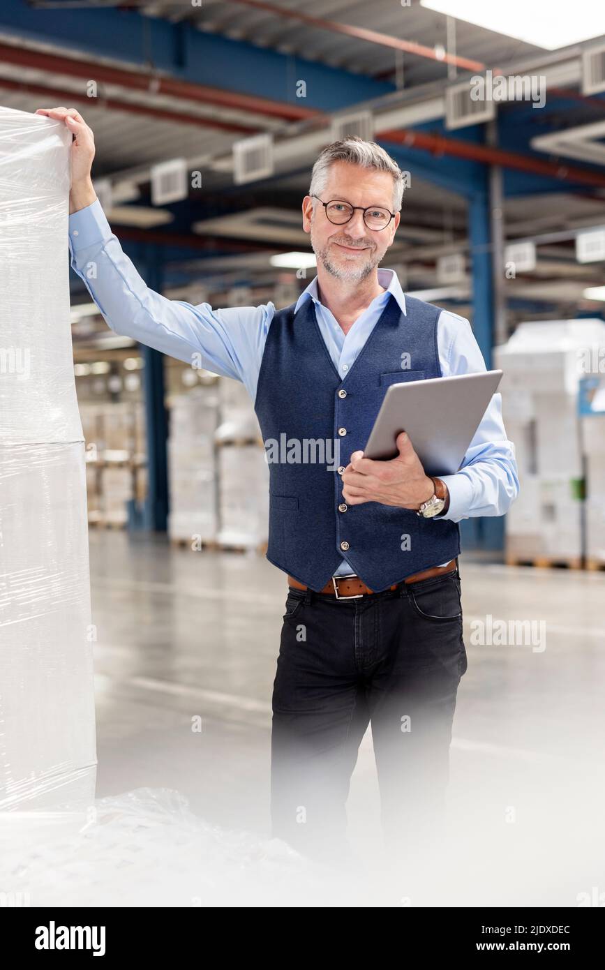 Un manager sorridente con un tablet PC in magazzino Foto Stock