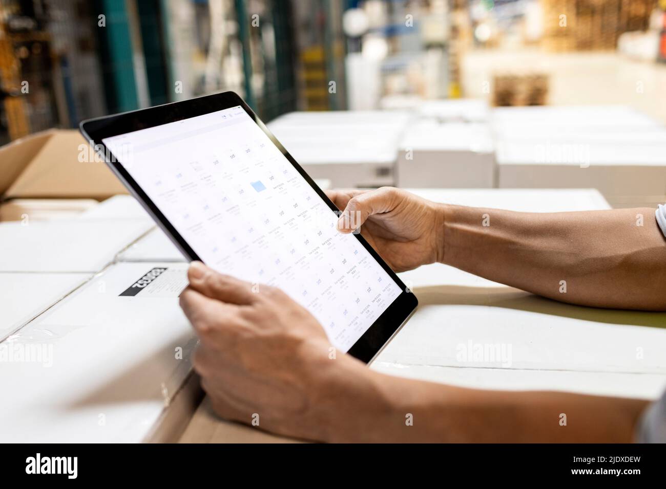 Le mani del lavoratore che controlla l'inventario sul tablet PC in magazzino Foto Stock