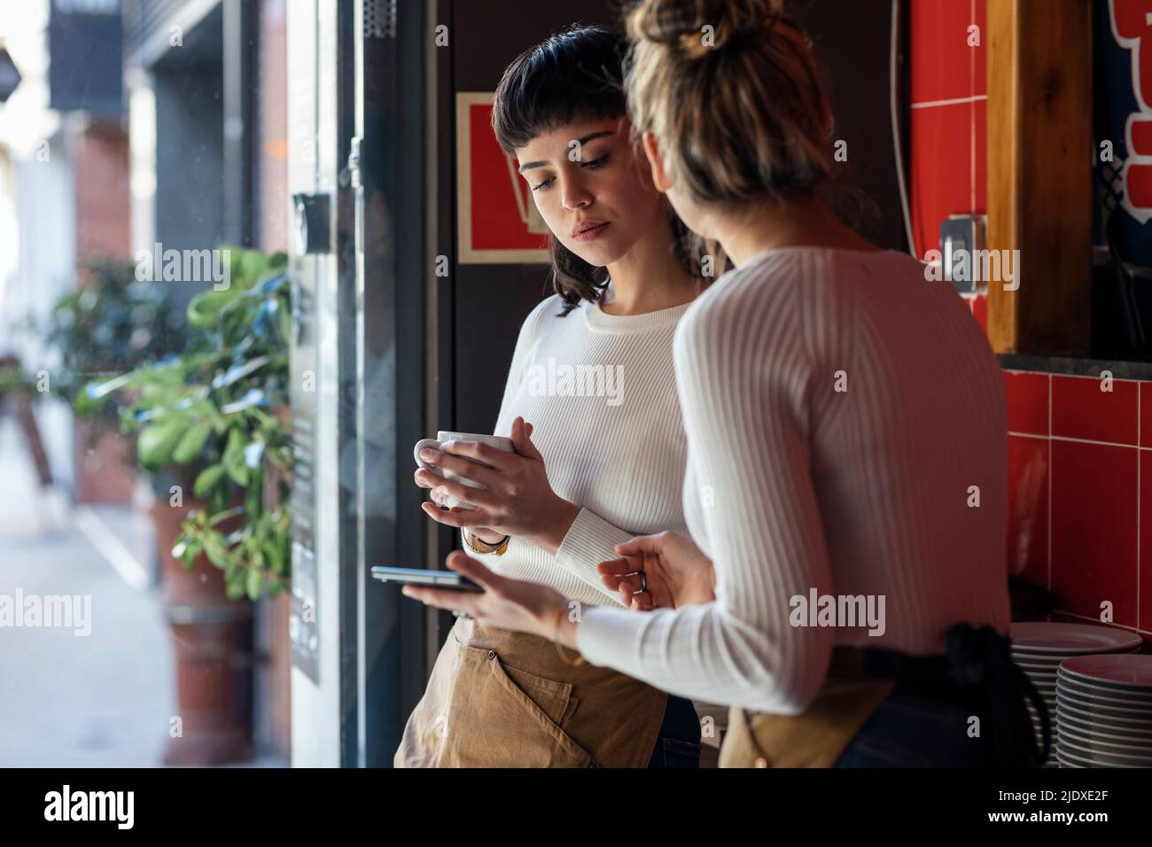 Il proprietario del ristorante che tiene un tablet PC discutere con il collega Foto Stock