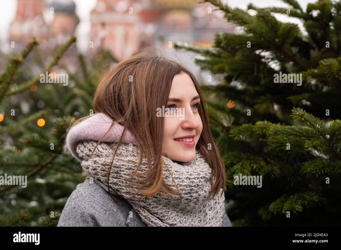 Donna sorridente con sciarpa giorno sognando da albero di Natale Foto Stock