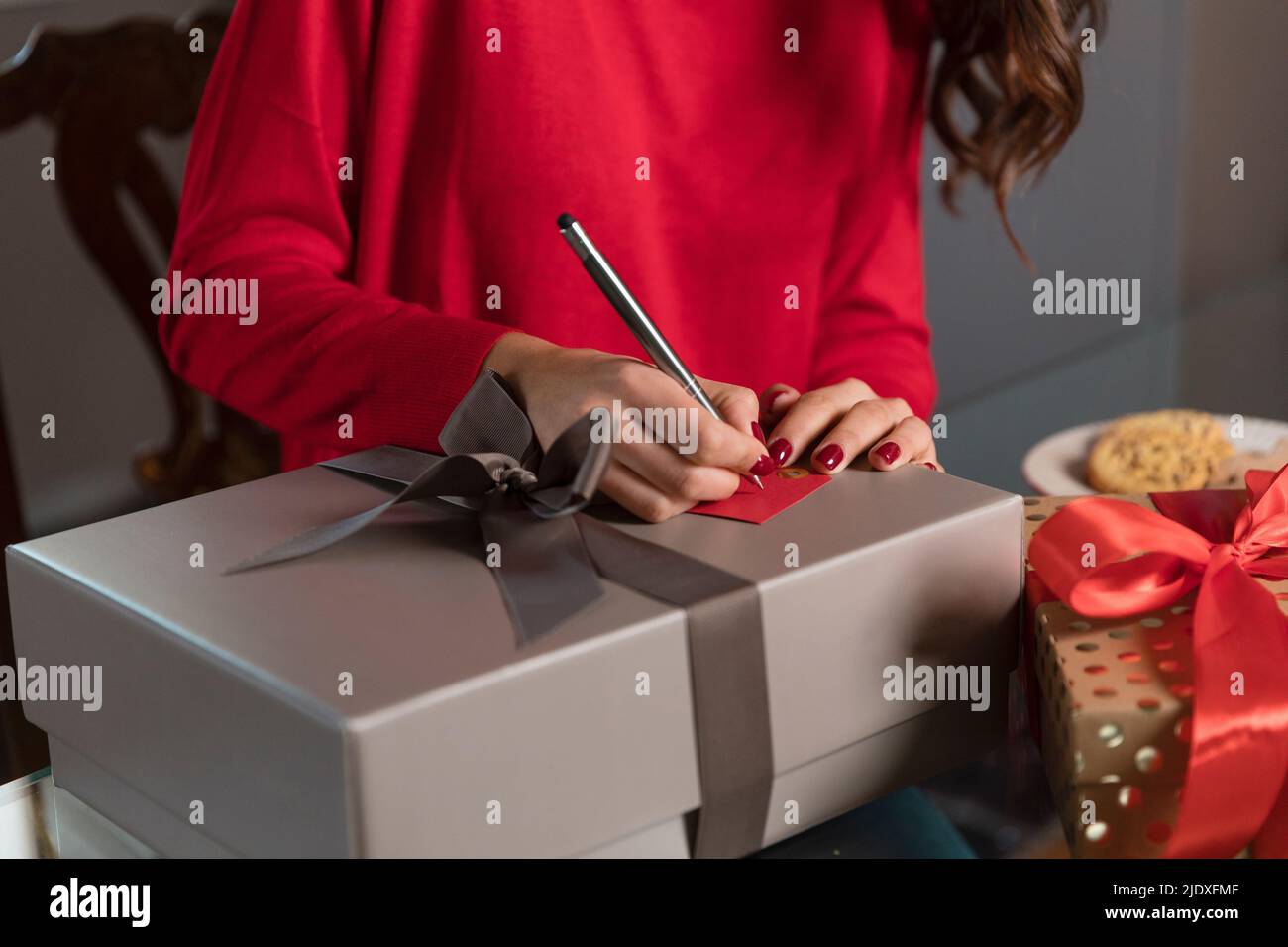 Giovane donna che scrive sul tag regalo per regalo di Natale a casa Foto Stock