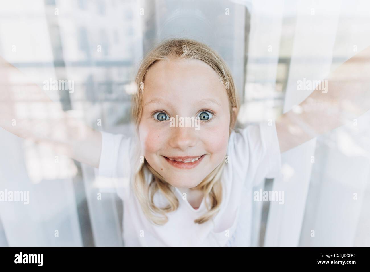 Ragazza felice che fa le facce viste attraverso la finestra Foto Stock