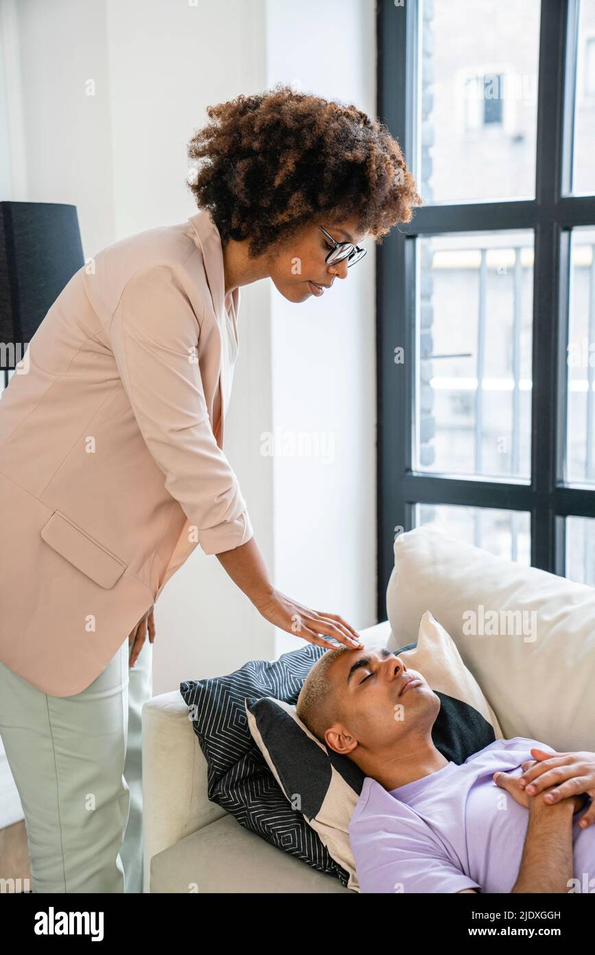 Psicologo che fa la terapia di ipnosi sul paziente sdraiato sul divano Foto Stock