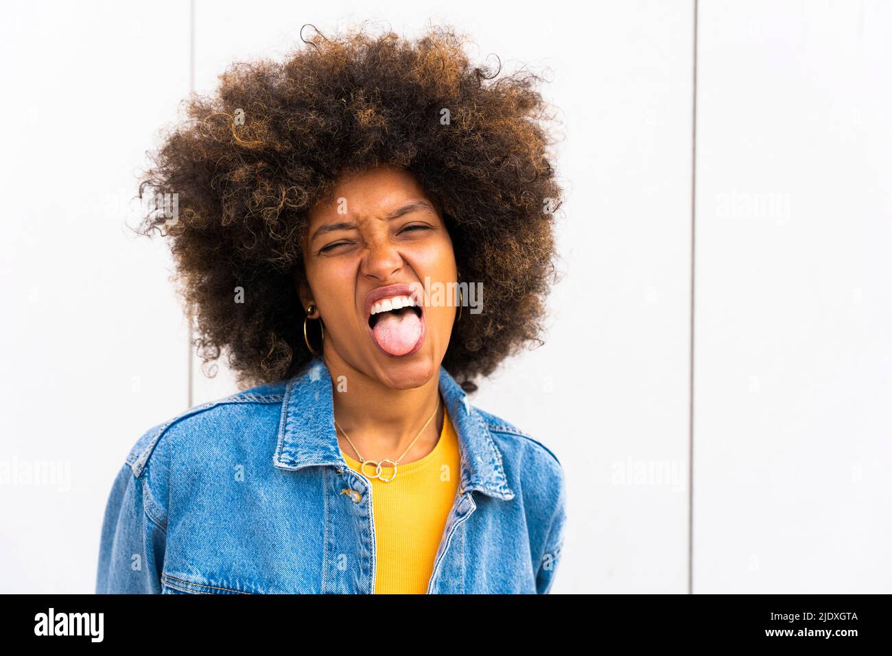 Afro donna che attacca la lingua davanti al muro Foto Stock