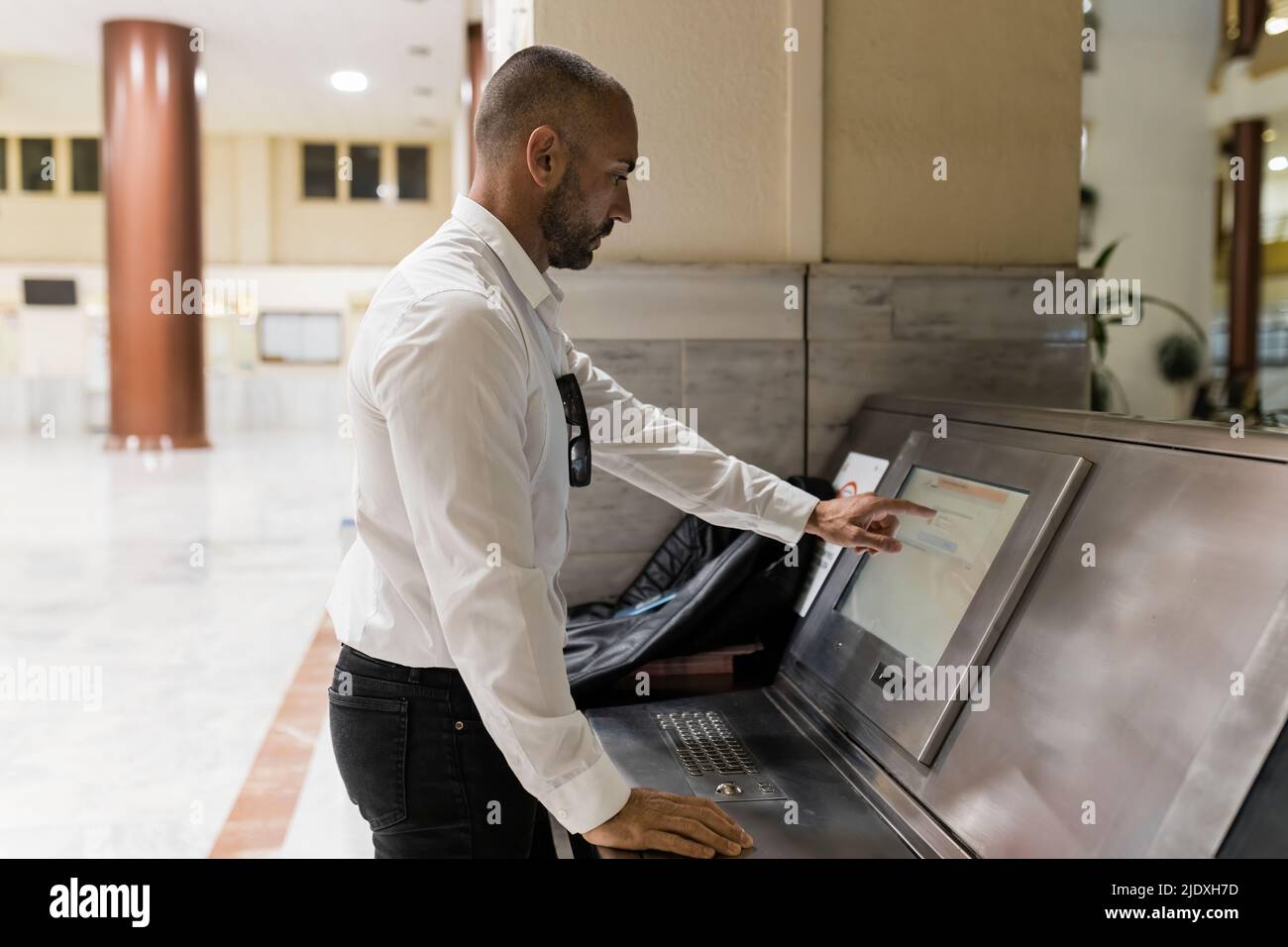 Uomo che usa un computer con schermo a sfioramento in hotel Foto Stock