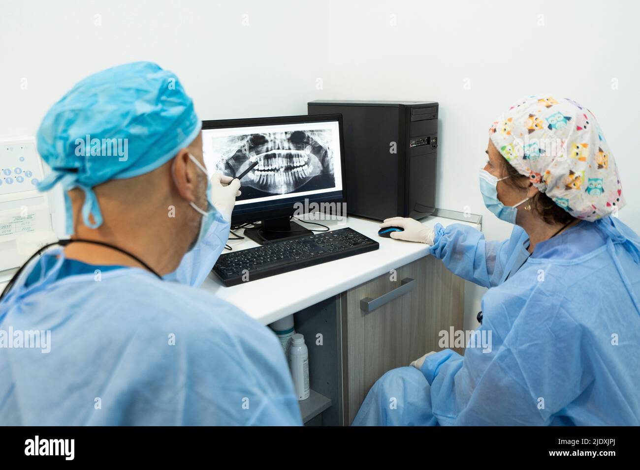 I dentisti analizzano i raggi X sullo schermo del computer presso la clinica Foto Stock