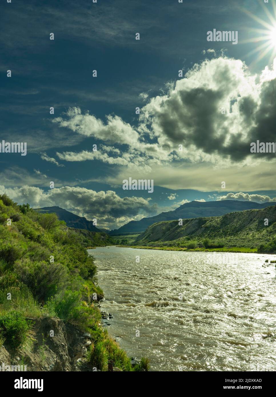 Una tempesta sul fiume Shoshone a Cody Wyoming. Ammira un'esplosione di sole con le nuvole scure nel cielo. Il fiume sta correndo velocemente guardando verso Yellowstone. Foto Stock