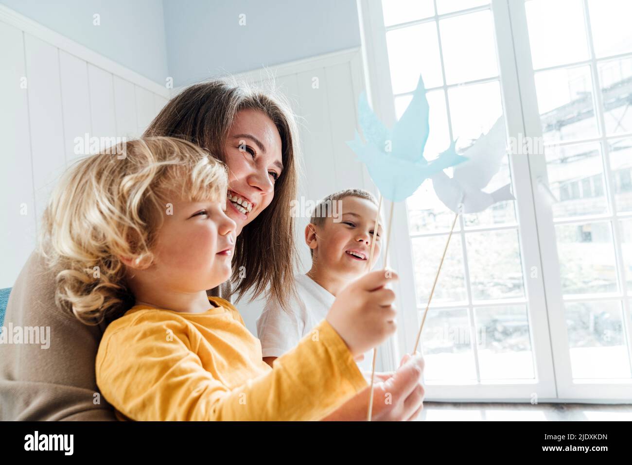 Madre e figlio felici che giocano con gli uccelli origami a casa Foto Stock