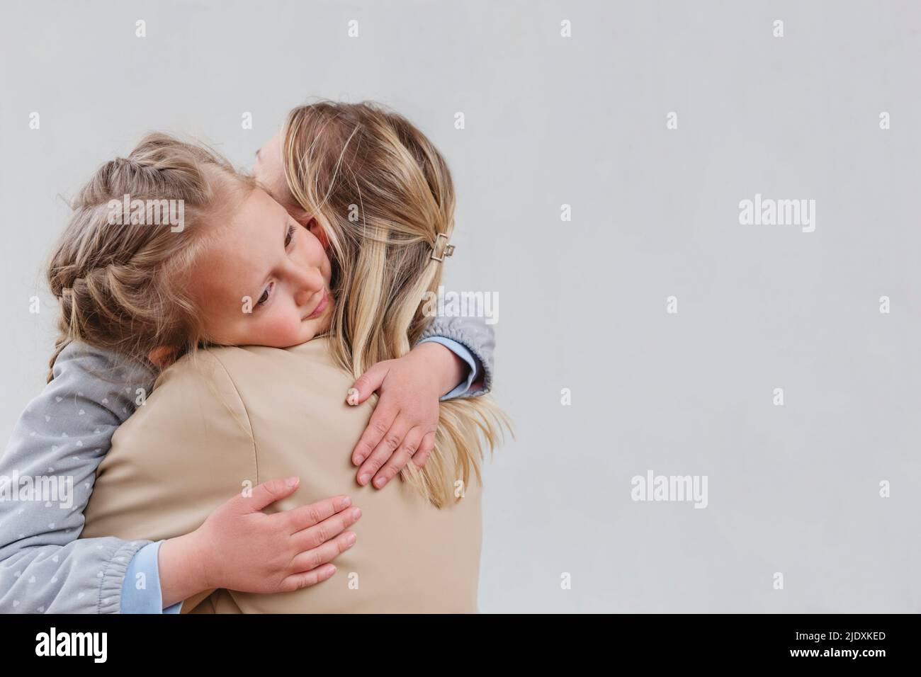 Figlia che abbraccia la madre su sfondo bianco Foto Stock