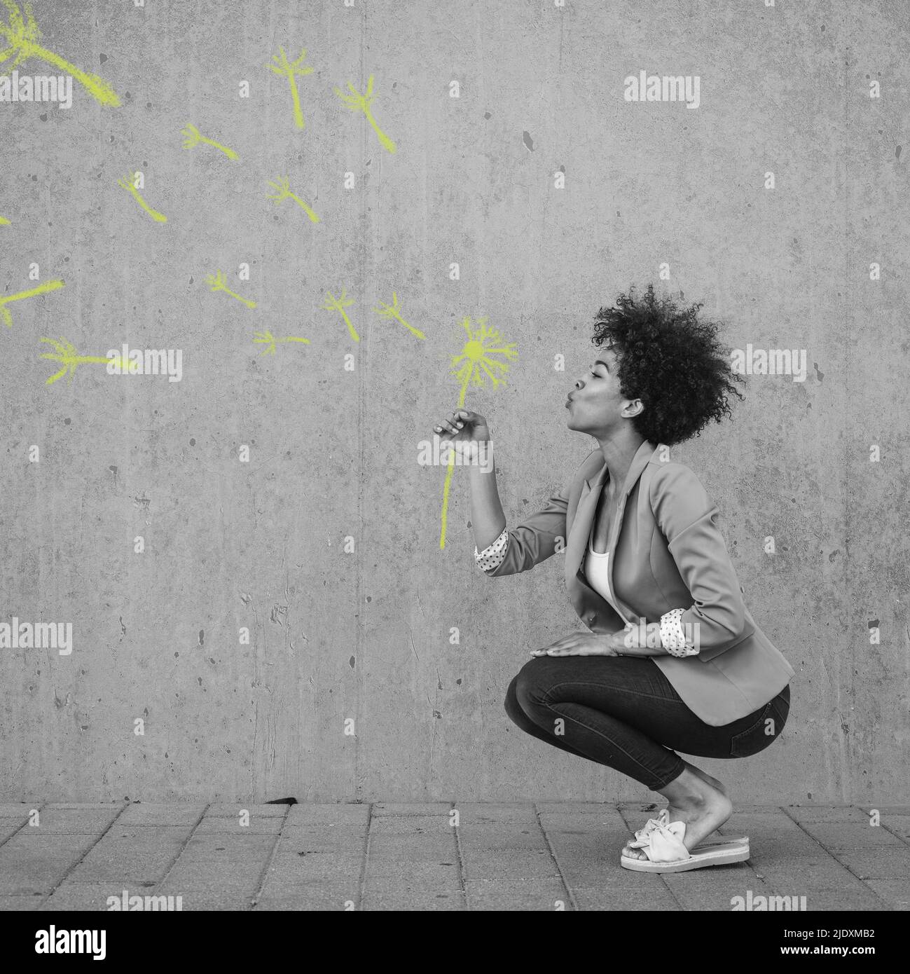 Donna accovacciata soffiando dipinto fiore palla soffio Foto Stock