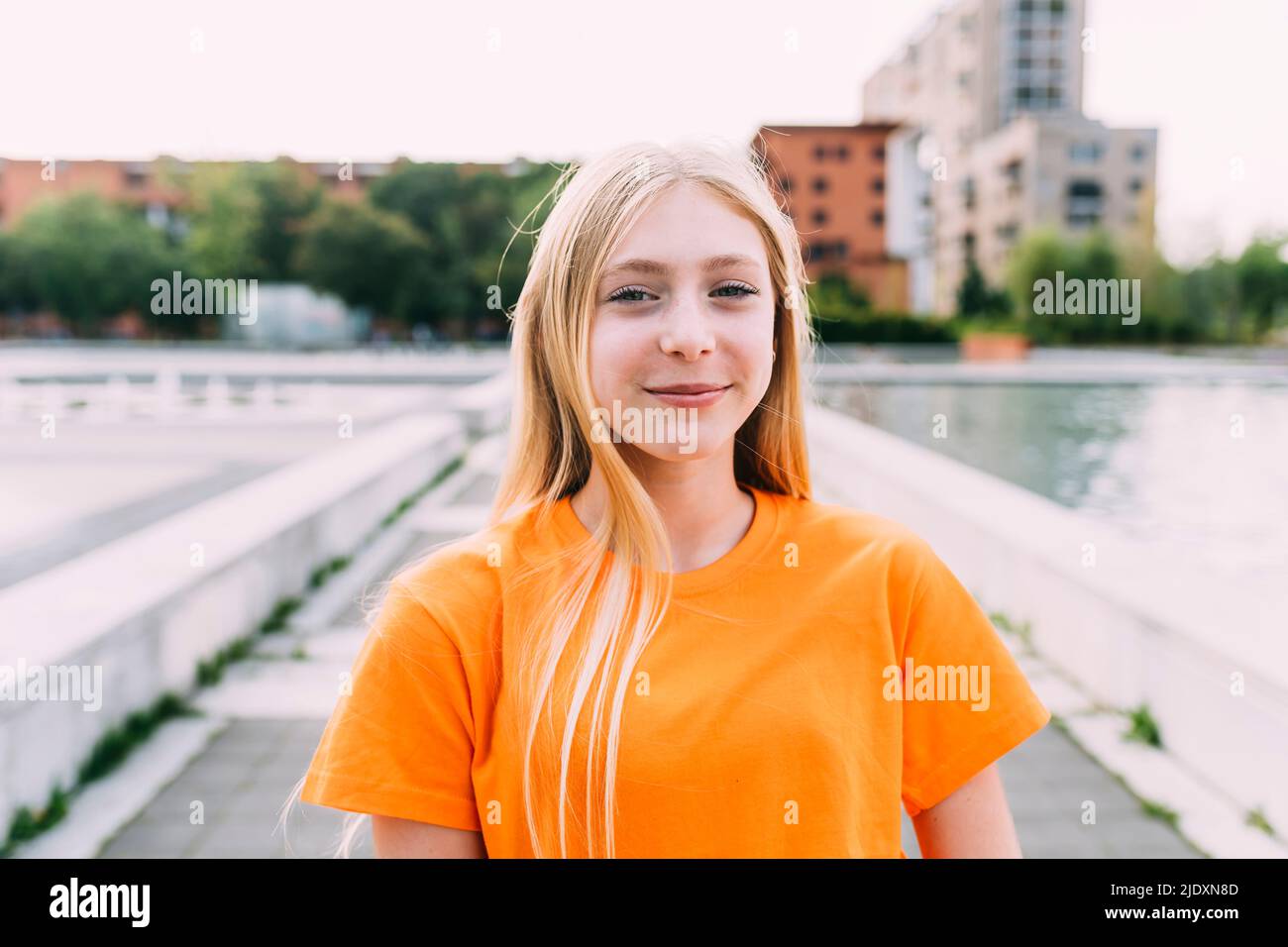 Ragazza felice con capelli biondi e maglietta arancione Foto Stock