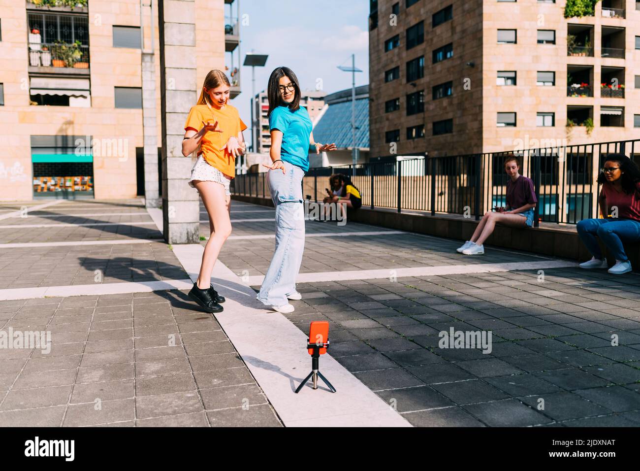 Le ragazze ballano filmando con lo smartphone il giorno di sole Foto Stock