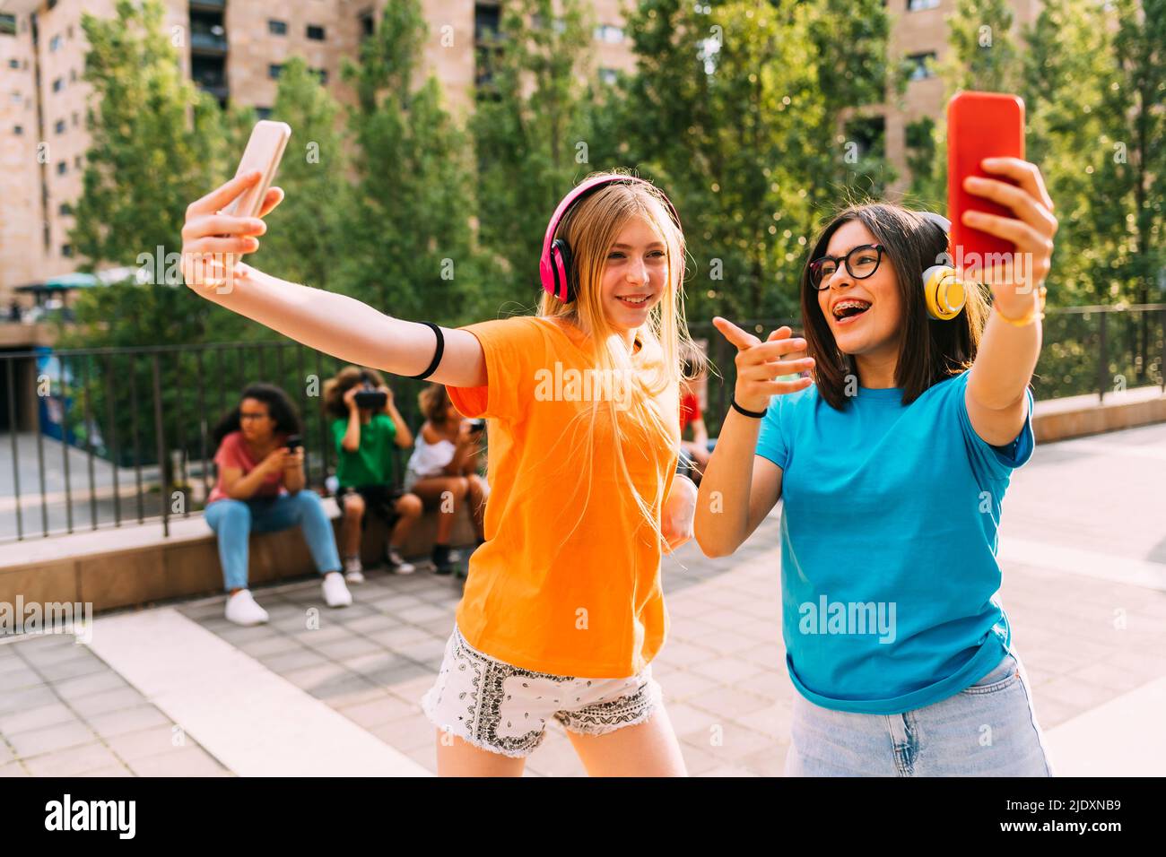 Gli amici che indossano cuffie wireless con lo smartphone Foto Stock