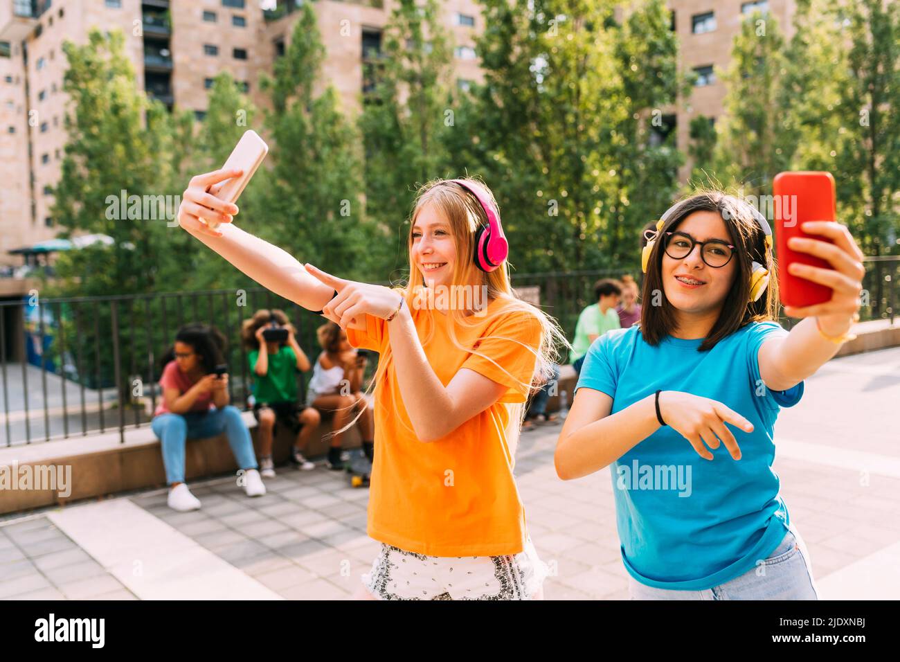 Buone ragazze che indossano cuffie wireless per filmare con smartphone Foto Stock