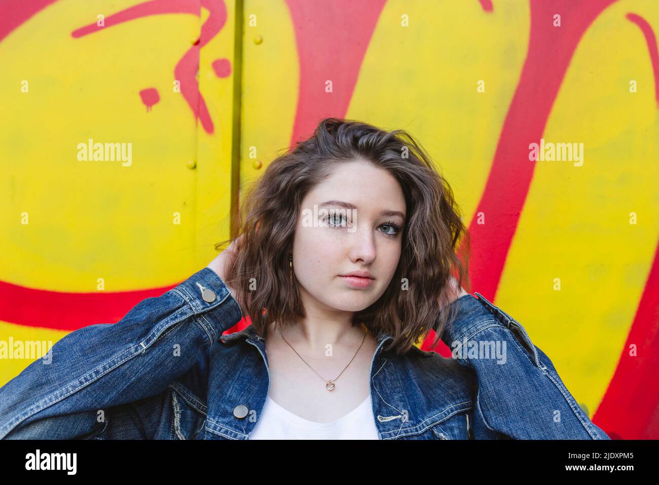 Ragazza adolescente con un atteggiamento fresco di fronte al muro graffiti Foto Stock