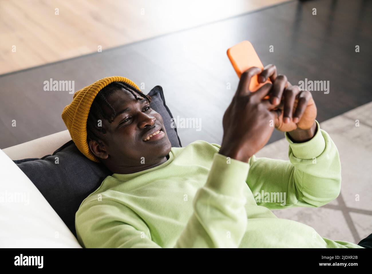 Uomo che utilizza un cellulare in salotto Foto Stock