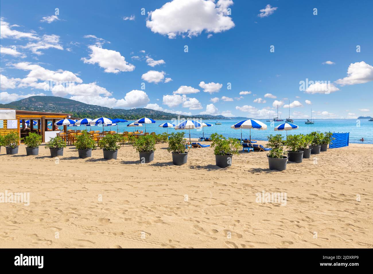 Sedie, lettini e ombrelloni lungo la Costa Azzurra presso la spiaggia sabbiosa di Port Grimaud, Francia, vicino a Saint-Tropez lungo il Mar Mediterraneo. Foto Stock