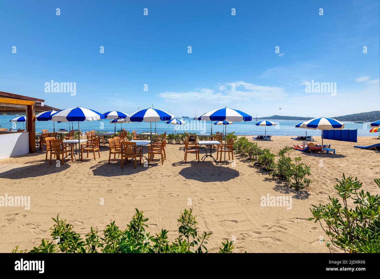 Sedie, lettini e ombrelloni lungo la Costa Azzurra presso la spiaggia sabbiosa di Port Grimaud, Francia, vicino a Saint-Tropez lungo il Mar Mediterraneo. Foto Stock