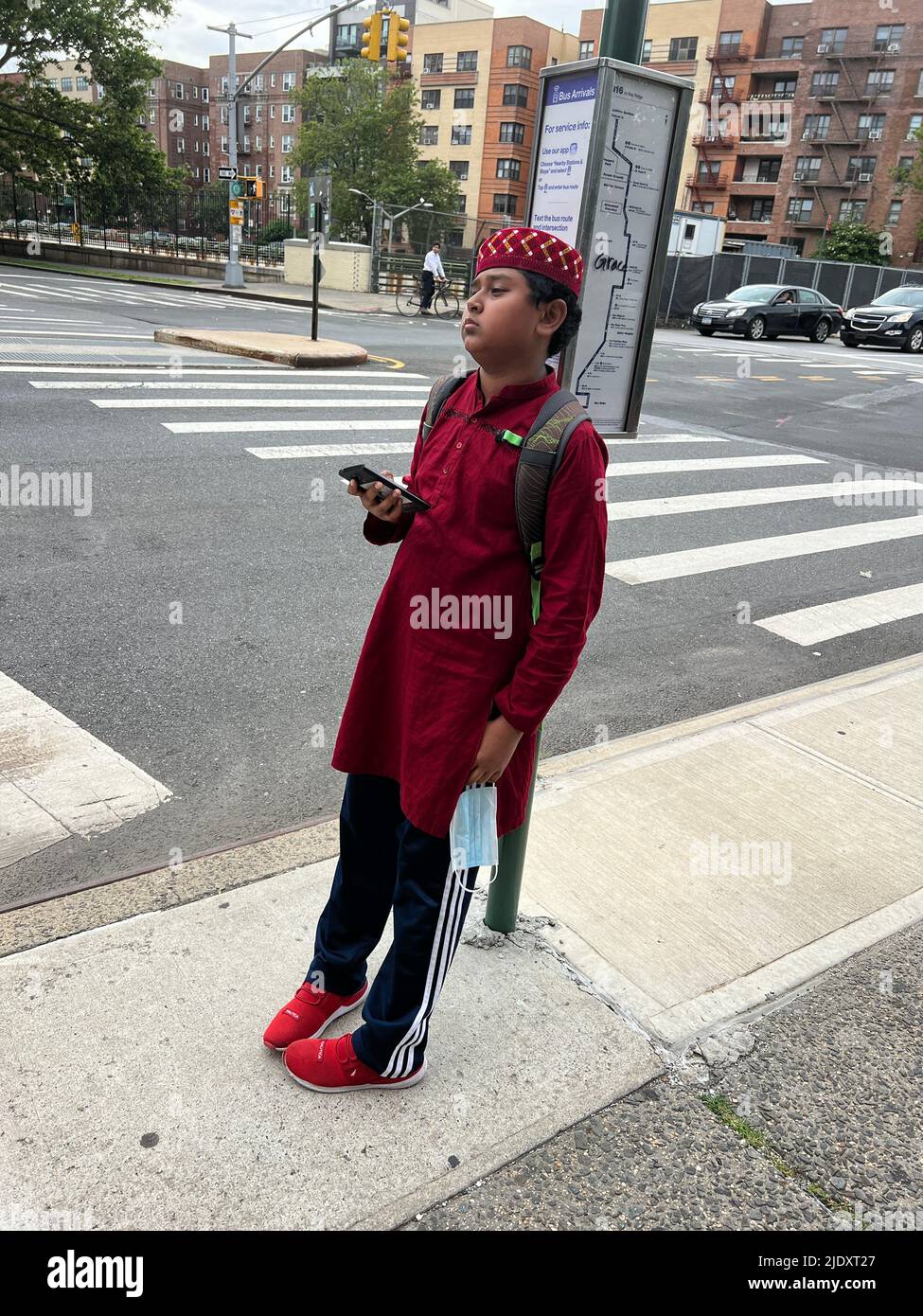 Ragazzo musulmano americano aspetta un autobus su Caton Avenue nel quartiere Kensington di Brooklyn, New york. Foto Stock