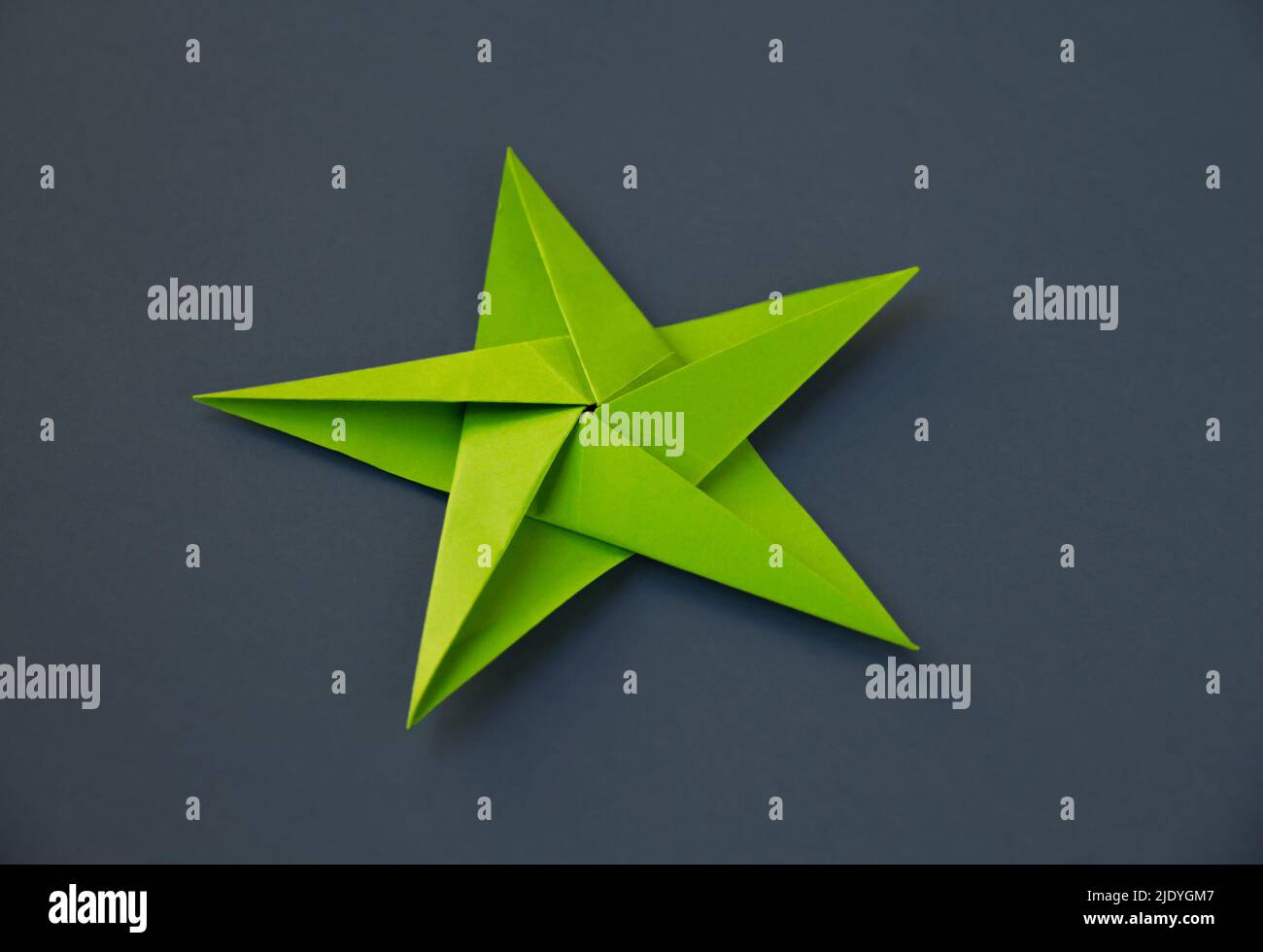 Carta verde stella origami isolato su uno sfondo bianco grigio. Foto Stock