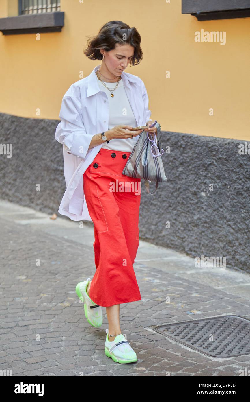 MILANO, ITALIA - 18 GIUGNO 2022: Donna con gonna rossa e fluorescente prima della sfilata di moda Federico Cina, Street style della settimana della Moda di Milano Foto Stock