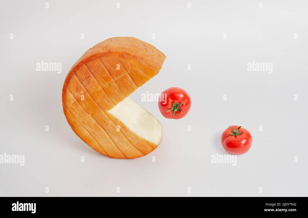 Rotolo di formaggio come un pak-man inghiottire i pomodori dal tavolo. Composizione concettuale creattiva Foto Stock