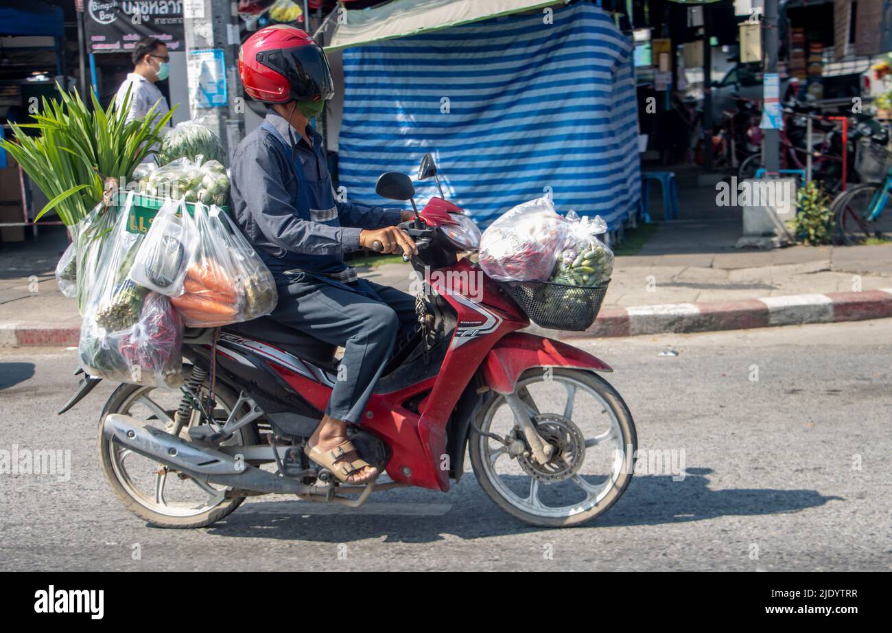 SAMUT PRAKAN, THAILANDIA, 19 2022 MARZO, Un uomo guida una moto per strada con acquisti in sacchetti di plastica Foto Stock