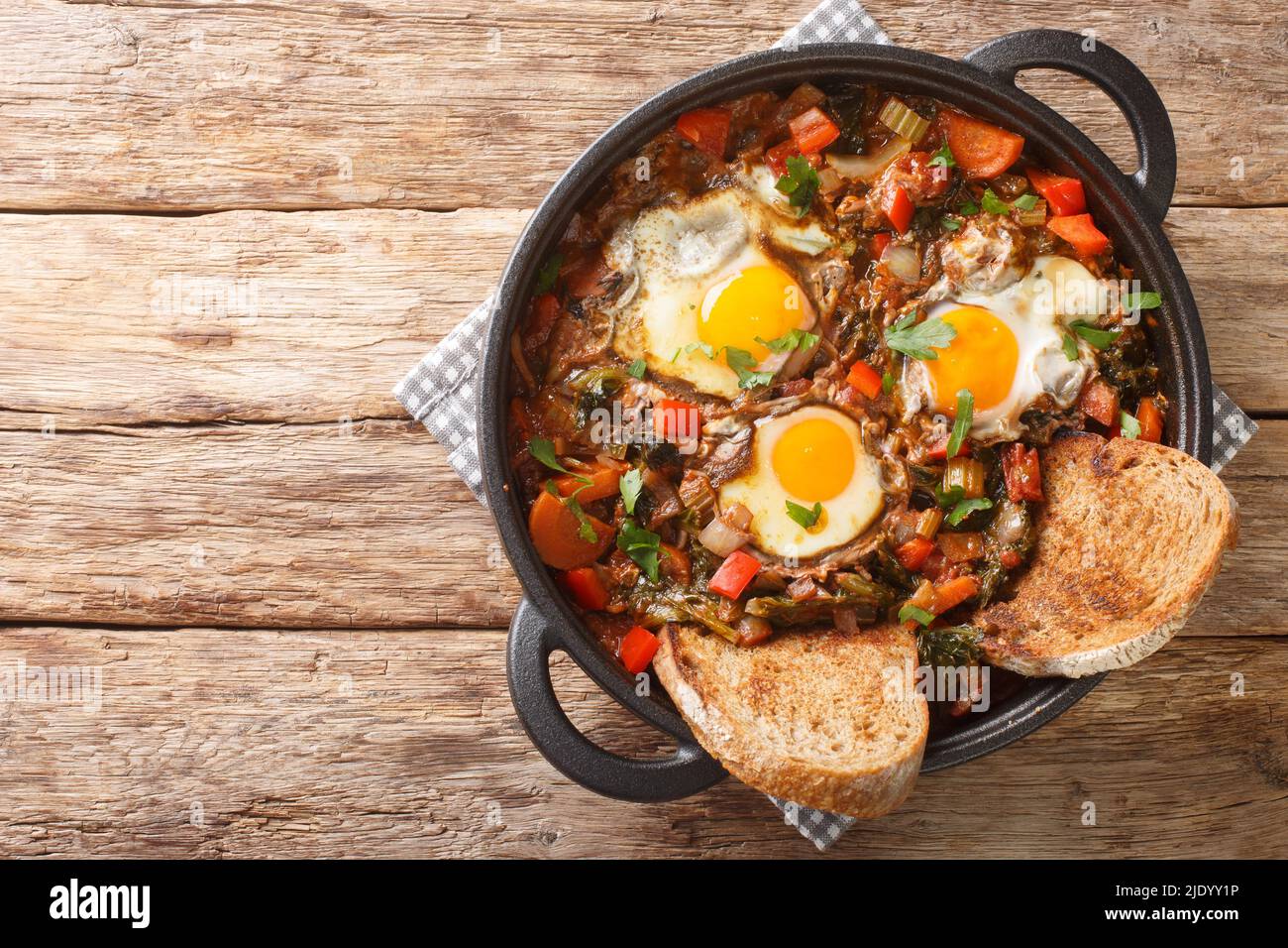 Zuppa di verdure con uova Acquacotta Maremmana servita con pane fatto in casa da vicino in una casseruola sul tavolo. Vista dall'alto orizzontale Foto Stock