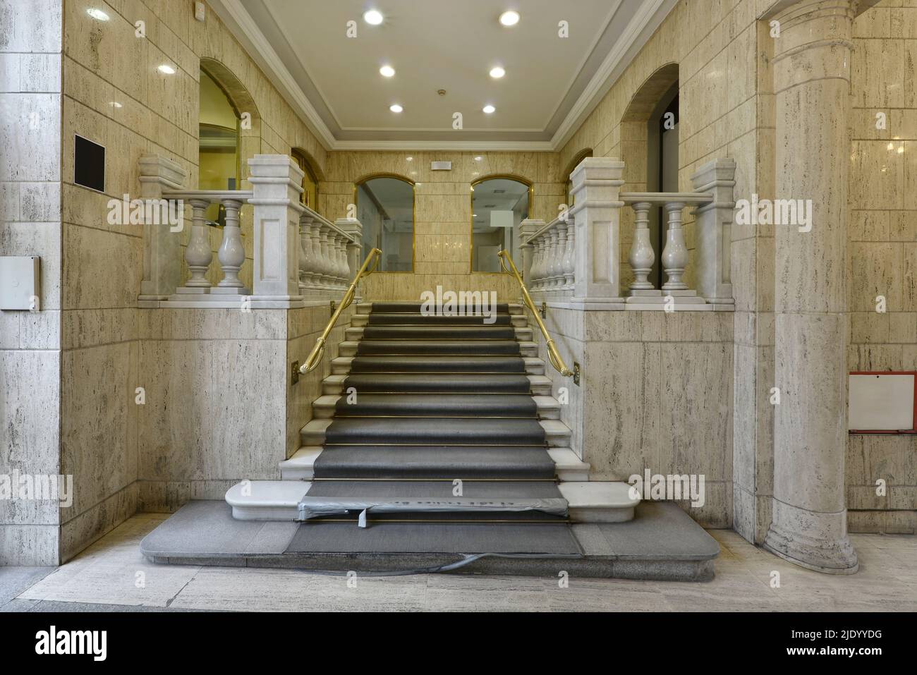 Scale con scalini e balaustre in marmo al piano terra di un palazzo con tappeti usurati Foto Stock
