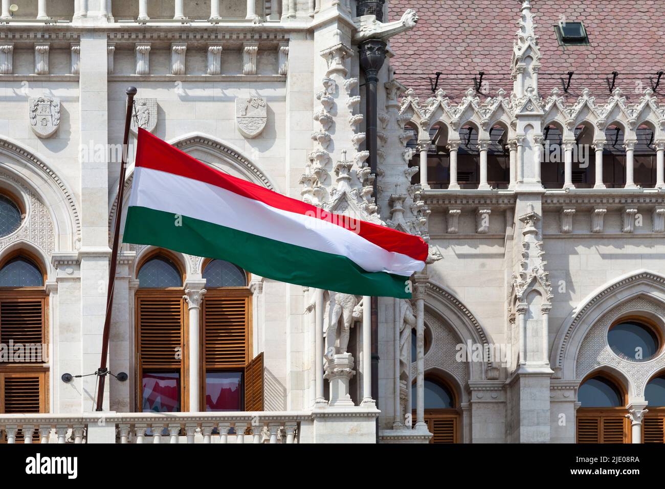 Bandiera ungherese che sventola su un balcone del Parlamento ungherese di Budapest. Foto Stock