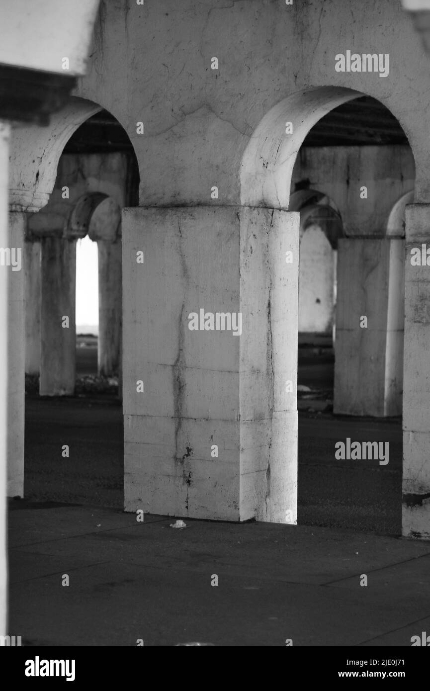 Un colonnato cittadino interno di colonne che tiene un ponte sospeso in bianco e nero. Foto Stock