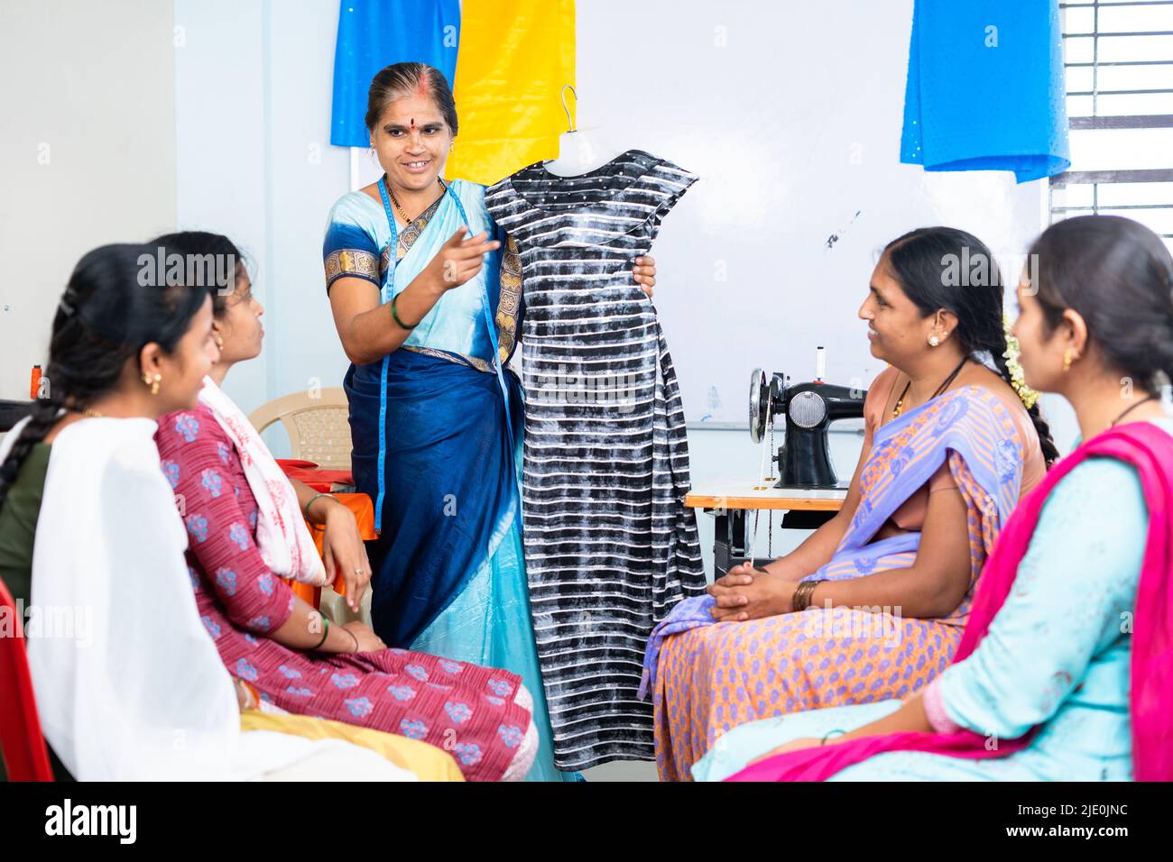 Donna che insegna la progettazione di tessuti agli studenti al centro di formazione su misura - concetto di apprendimento, occupazione e workshop. Foto Stock