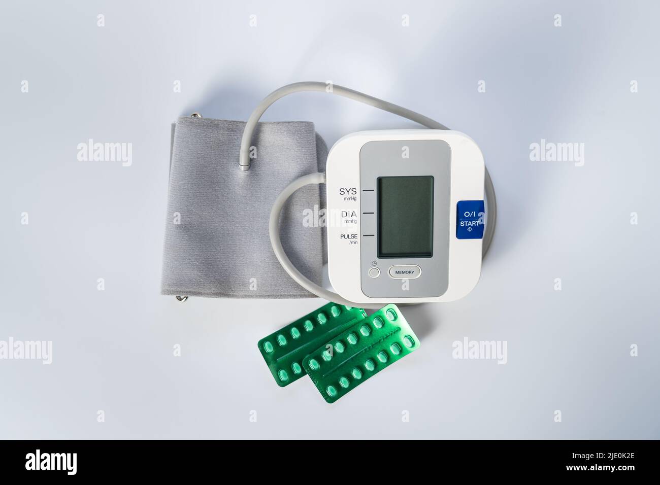 Monitor della pressione sanguigna per prendere la pressione sanguigna e pillole per abbassarla su sfondo bianco. Foto Stock