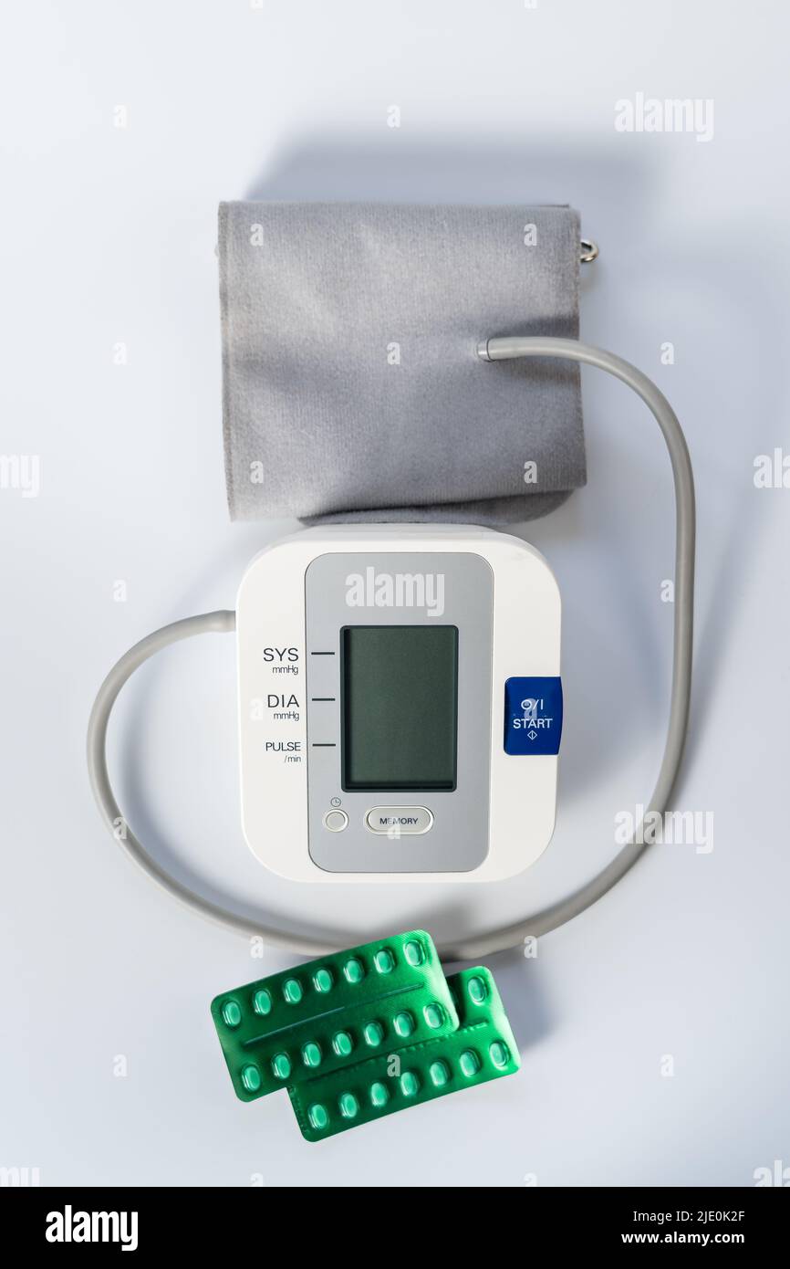 Pillole per abbassare la pressione sanguigna e una macchina per prendere la pressione sanguigna. Foto Stock
