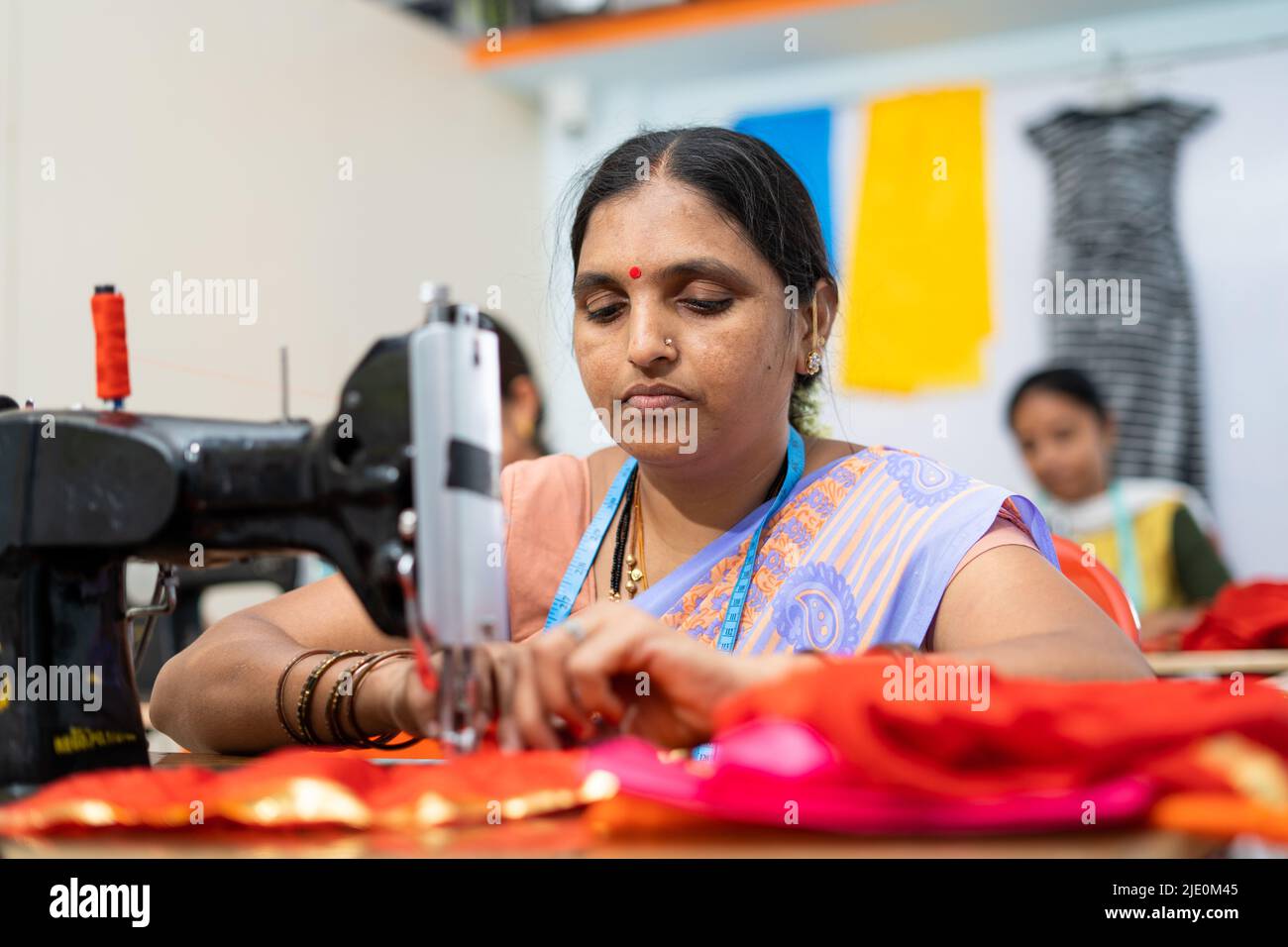 I dipendenti di abbigliamento lavorano seriamente sul cucito di stoffa in fabbrica-concetto di lavoro duro, donna autonoma impiegato e piccola impresa. Foto Stock