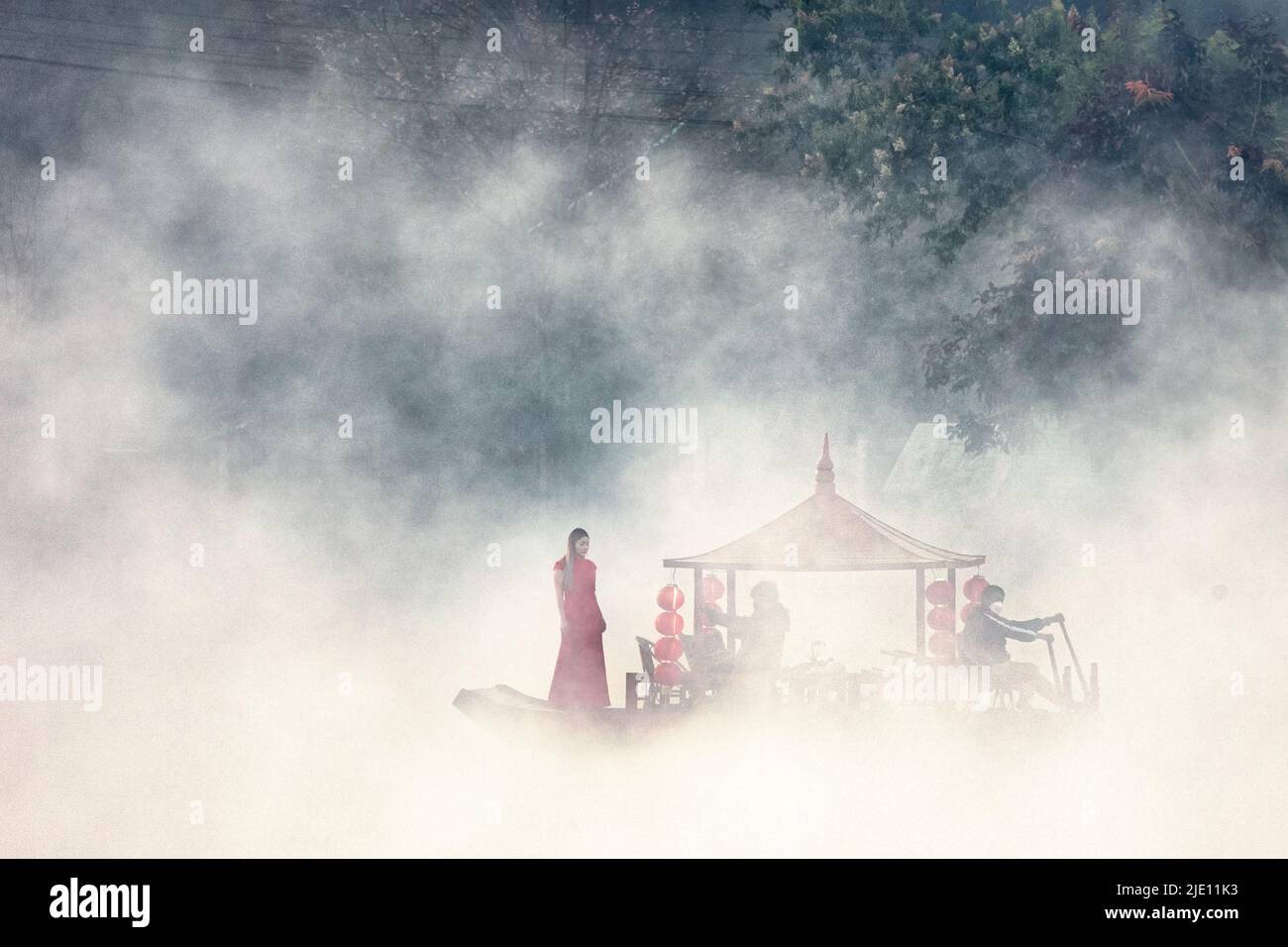 Donna non identificata che si posa in una barca turistica cinese che naviga sul lago Ban Rak Thai all'alba, in Thailandia Foto Stock