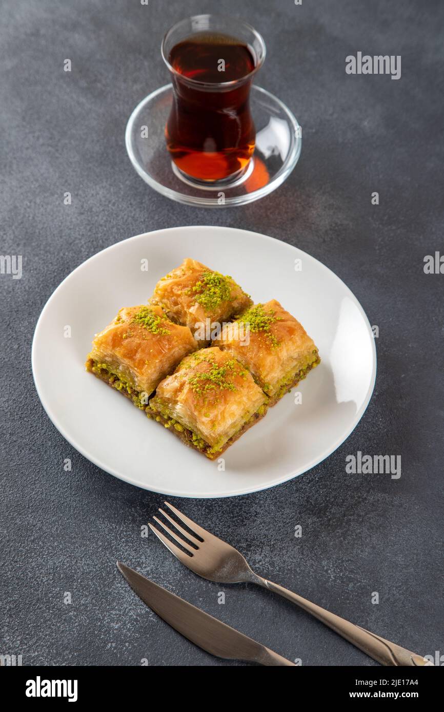 Tradizionale pistacchio baklava con tè turco. Un piatto di baklava su sfondo scuro Foto Stock