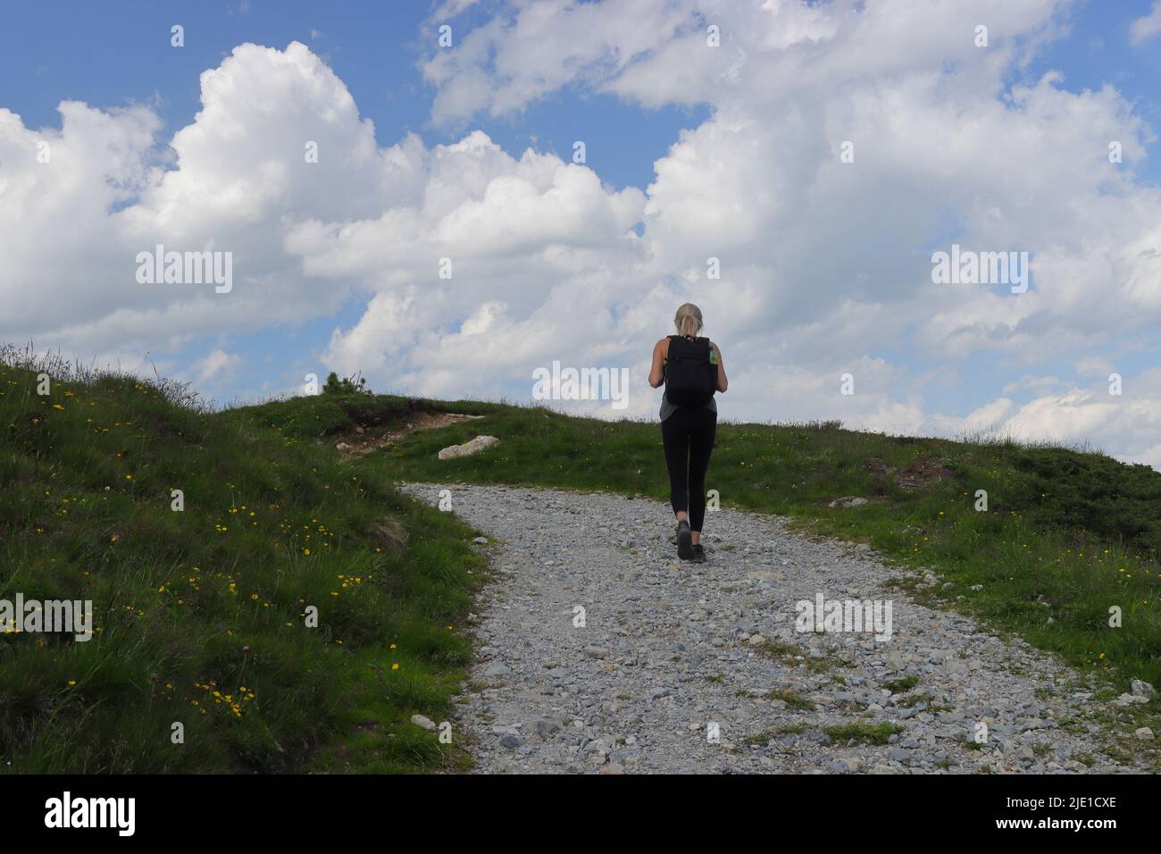 Una giovane donna fa un'escursione con uno zaino sulla schiena su un sentiero di alta montagna nello Zillertal Foto Stock