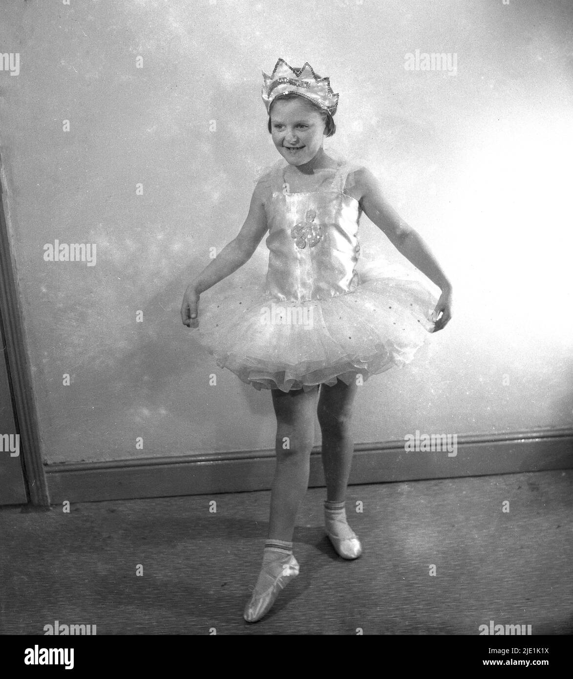 Bambina ballerina in un tutù rosa e scarpe da punta in posa in uno studio  bianco