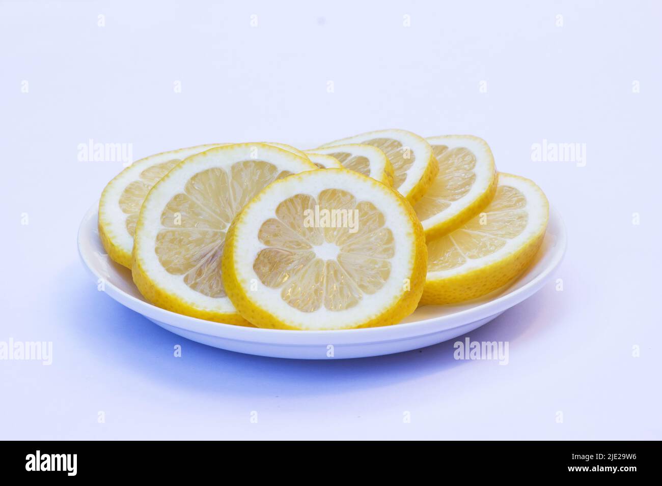 Limoni a fette su un piatto bianco isolato su sfondo bianco Foto Stock