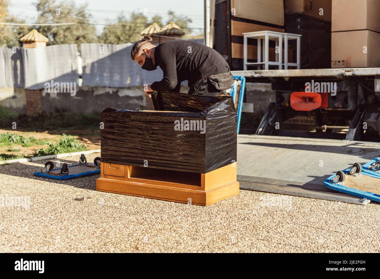 lavoratore che avvolge un pezzo di legno di mobili con un involucro di plastica Foto Stock