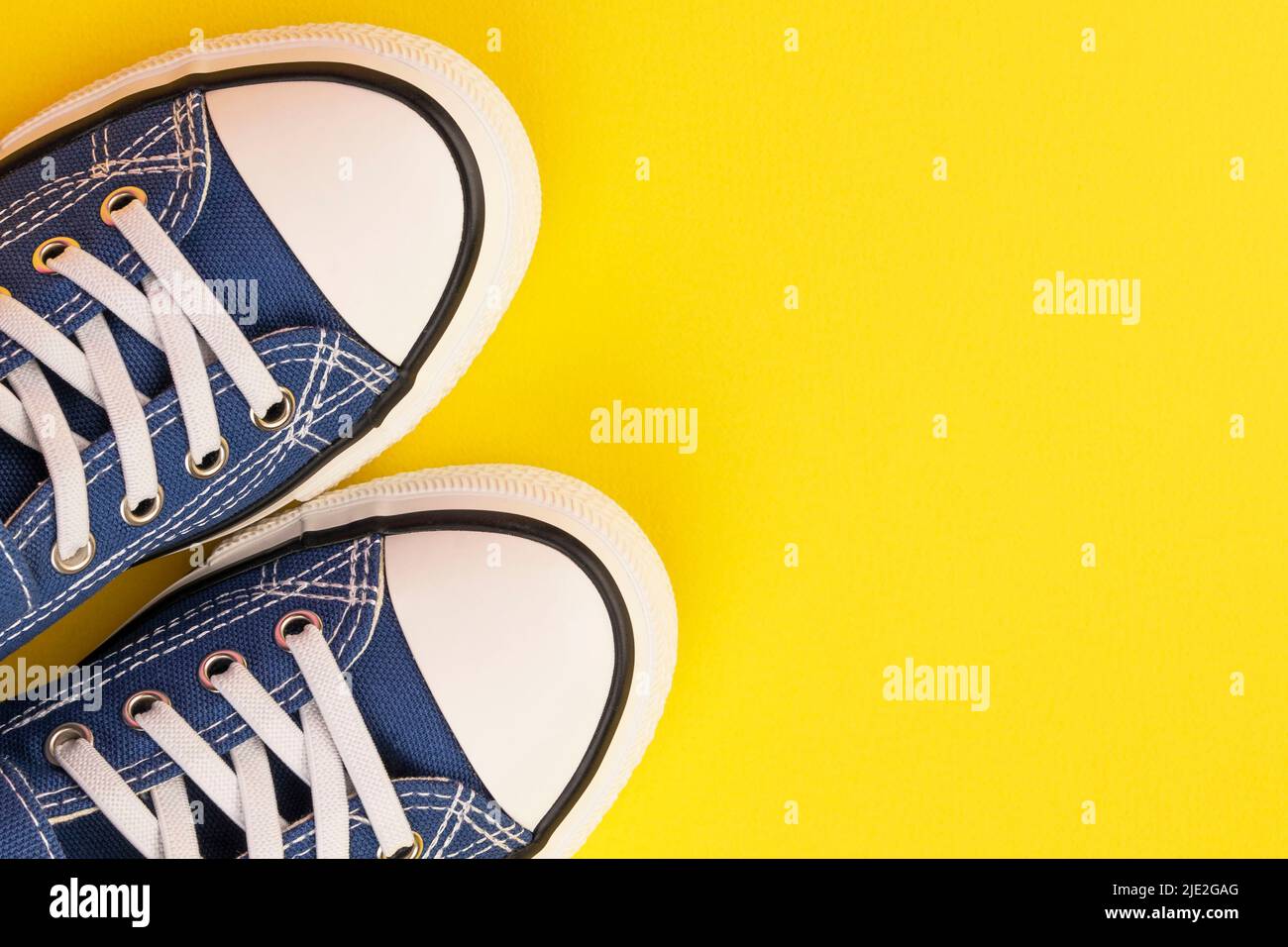 un paio di sneaker blu su sfondo giallo Foto Stock