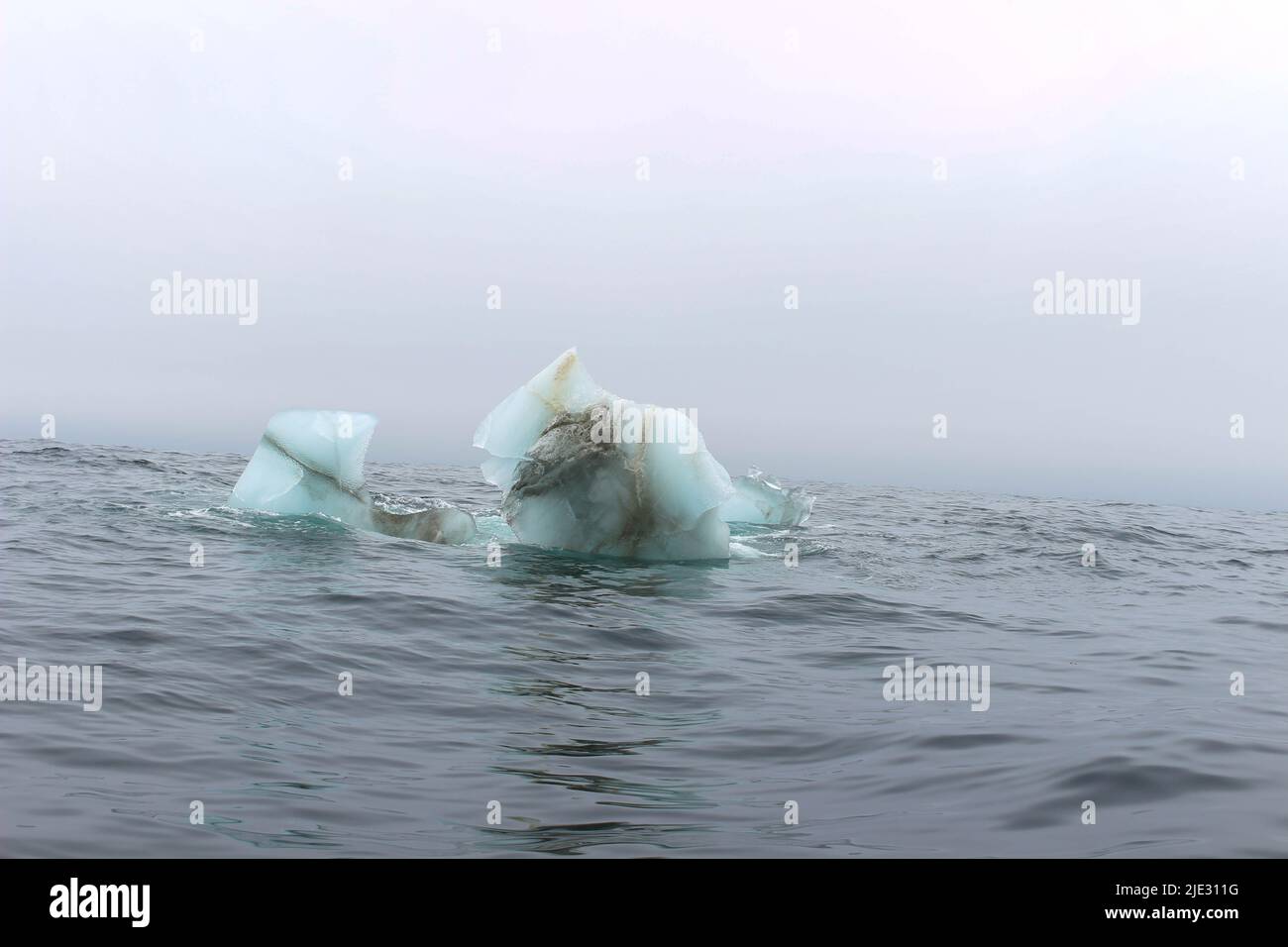 L'onda si schiantando contro un piccolo iceberg che galleggia in mare Foto Stock