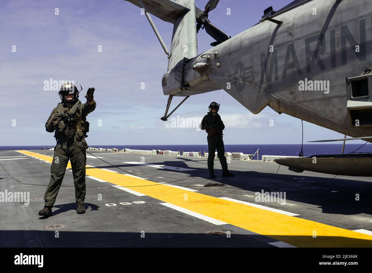 I Marines statunitensi assegnati a Marine Heavy Helicopter Squadron 462, Marine Air-Ground Task Force 7 (MAGTF-7) 'Ripper', comunicano con i segnali a mano e a braccio durante le qualifiche di atterraggio sul ponte a bordo della nave d'assalto anfibio USS Essex (LHD2), nell'Oceano Pacifico, 22 giugno 2022. Il MAGTF-7 fornisce una formazione realistica e pertinente che aumenta le capacità dei partecipanti di pianificare, comunicare e condurre operazioni marittime complesse in modo efficiente ed efficace. (STATI UNITI Foto del corpo marino di Lance CPL. Brayden Daniel) Foto Stock