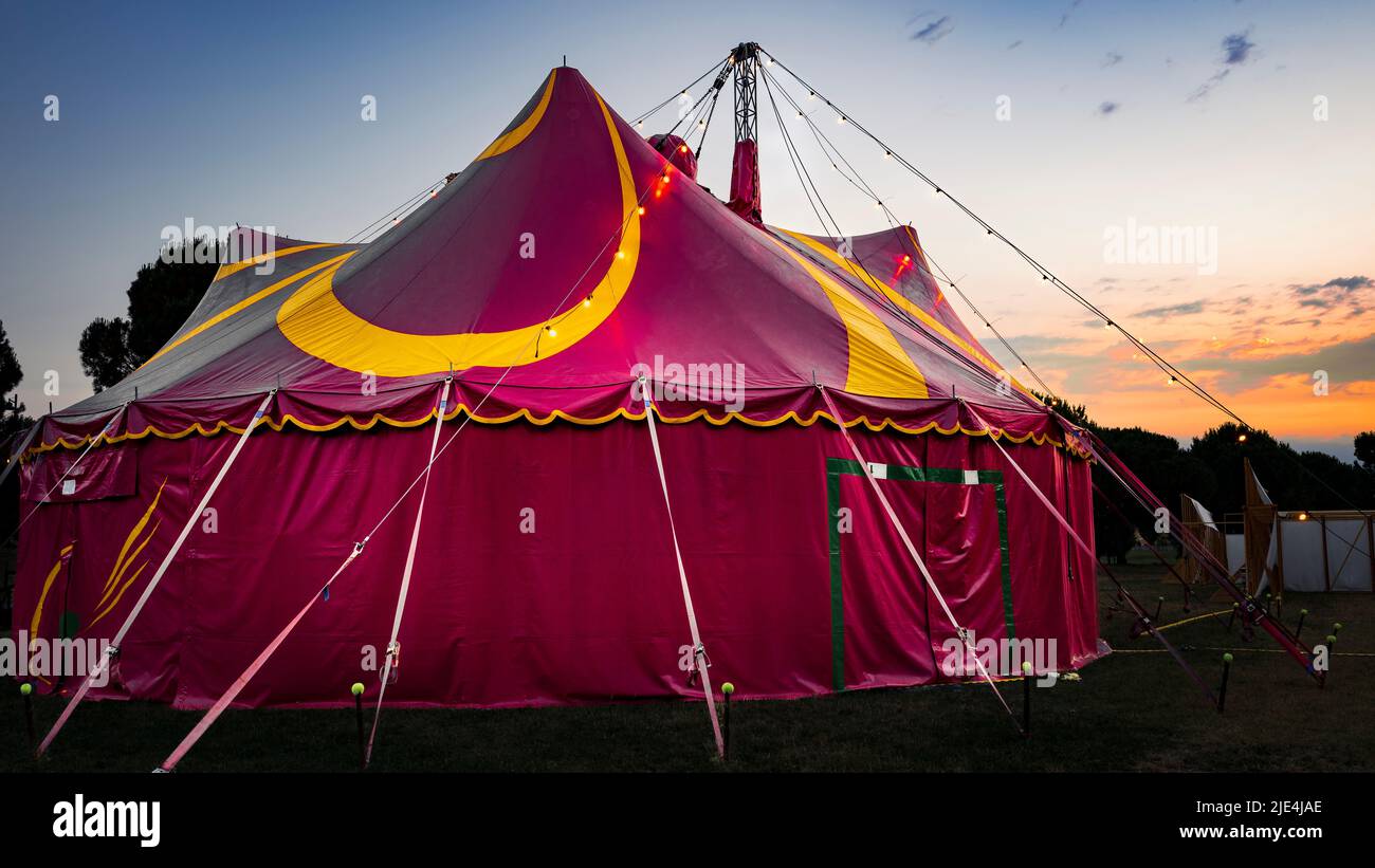 Dawn su una tenda rossa da circo gialla montata su un parco cittadino. Foto Stock