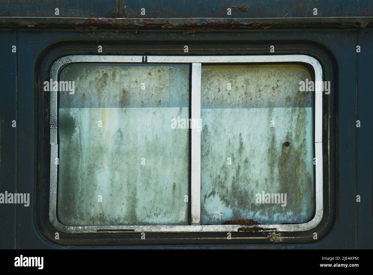primo piano della vista frontale del vecchio finestrino dell'auto arrugginito con telaio cromato metallico e vetro opaco sporco di forma rettangolare Foto Stock