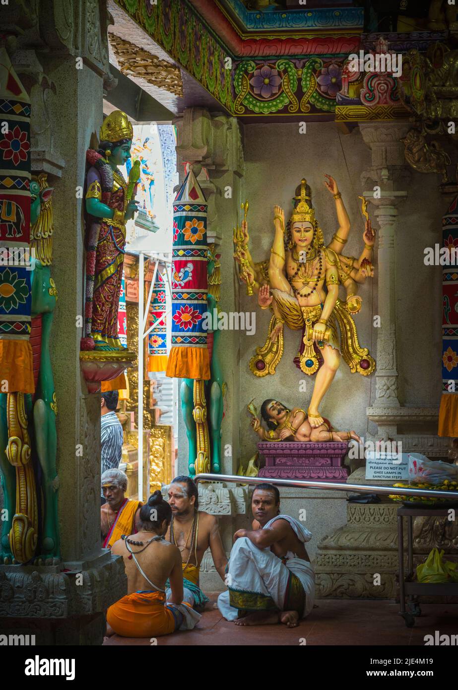 Sacerdoti rilassarsi di fronte alle divinità all'interno del tempio di Sri Veeramakaliamman, Serangoon Road, Little India, Repubblica di Singapore. Questo tempio indù è acceso Foto Stock